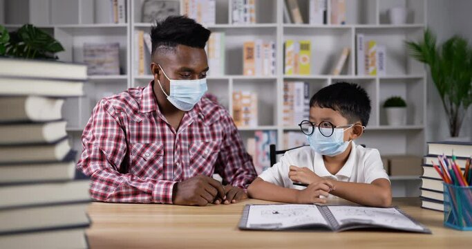 Young african teaching asian boy during quarantine at home