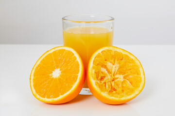 Glass with orange juice, one half of orange with juice and the other half of squeezed orange
