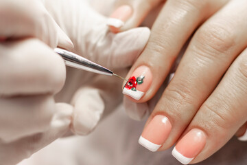 Manicure. White French jacket and red flower design gel paints on the nails of a young girl. Nail care in a beauty salon. Close-up