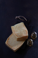 Two large pieces of hard cheese on black background.Hard cheese.Spice set made of metal. Top view. Free space