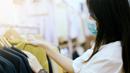 Woman wear protective mask shopping in clothing store.