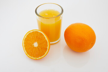 Glass with orange juice, a half of an orange and a whole orange
