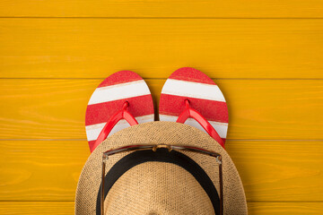 Above photo of sandals sunglasses and sunhat isolated on the yellow wooden background