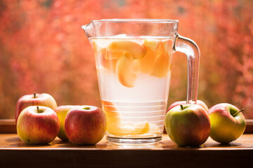 Jug full of fresh apple compote surrounded with nice red apples
