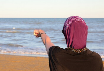 young Woman with a veil to cover her hair while pointing to the horizon with her index finger on...