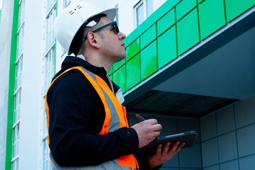 Builder inspects the new building, writing down comments in the tablet.. Building inspector....