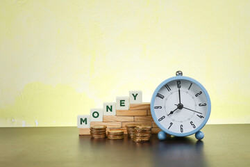 Money and time concept.  Block letters on Money on the wooden blocks with stacked coins and an...