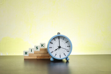 Risk and time concept.  Block letters on Risk on the wooden blocks with an alarm clock at the side
