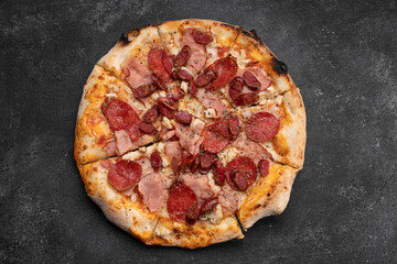 Four meat pizza on a dark concrete background