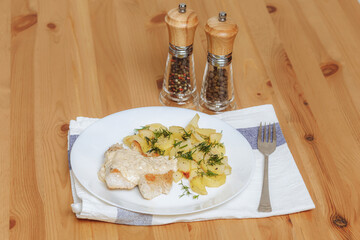 Roast turkey fillet with potatoes on plate, wooden table