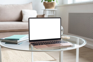 Laptop with blank white screen on the desk, mock up. Personal laptop computer on the table in living room with modern interior. Home work concept