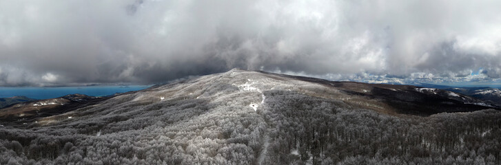 180 degree photo of the beech forest of the Nebrodi mountains in Sicily during a light snowfall in early spring. View of Etna. Monte Soro and the Aeolian Islands with the Tyrrhenian Sea. 