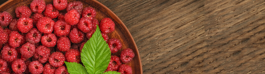 A bunch of red raspberries in a big plate with copy space banner