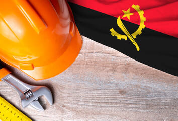 Angola flag with different construction tools on wood background, with copy space for text. Happy...