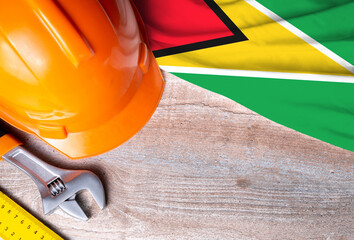 Guyana flag with different construction tools on wood background, with copy space for text. Happy Labor day concept.