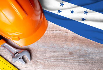 Honduras flag with different construction tools on wood background, with copy space for text. Happy Labor day concept.