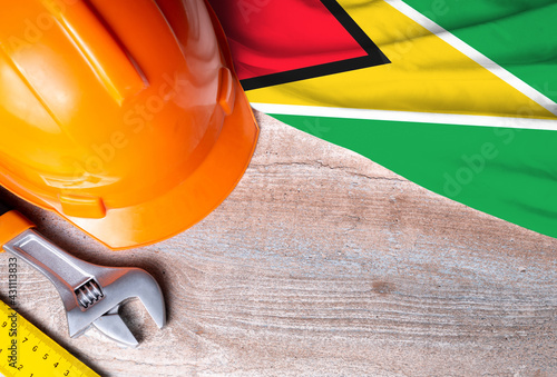 Guyana flag with different construction tools on wood background, with copy space for text. Happy Labor day concept.