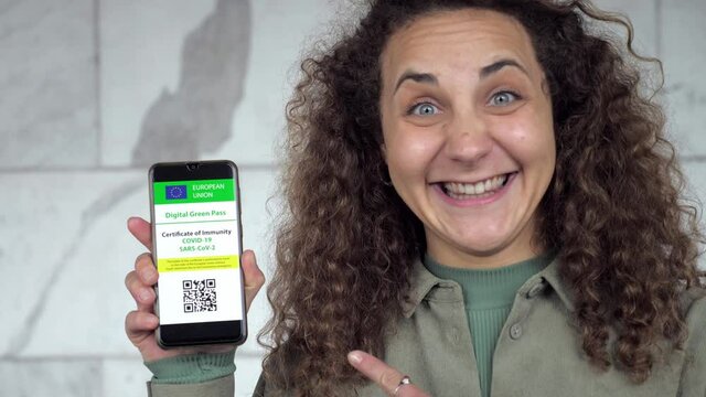 young woman happy to be able to return to travel shows the green pass on phone