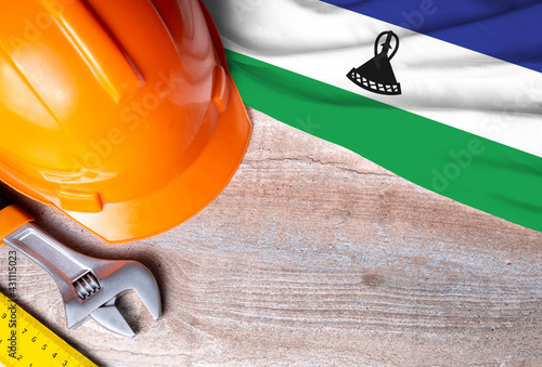 Lesotho flag with different construction tools on wood background, with copy space for text. Happy Labor day concept.