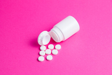 Flatley, white pills and jar on pink paper background copy space.