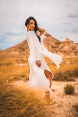 Fototapeta na wymiar Young brunette Caucasian model in a white dress and a black bikini enjoying in the beautiful desert