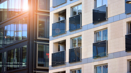 A residential building and an adjacent office building. Modern urban development. Buildings against blue sky and sun light. 