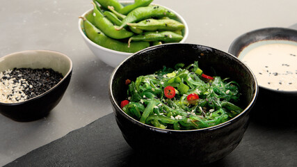 Wakame seaweed with sesame and chilli on gray background. Asian food concept.