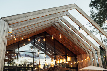 Evening illumination in the courtyard with the background of a modern wooden house