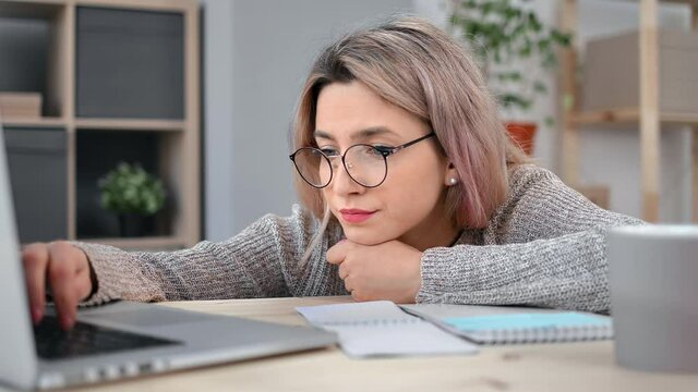 Depressive female office worker lazy typing use laptop lying on desk feeling tiredness overworked