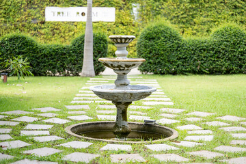 Obraz premium The fountain in the middle of the garden has a stone walkway surrounding it.