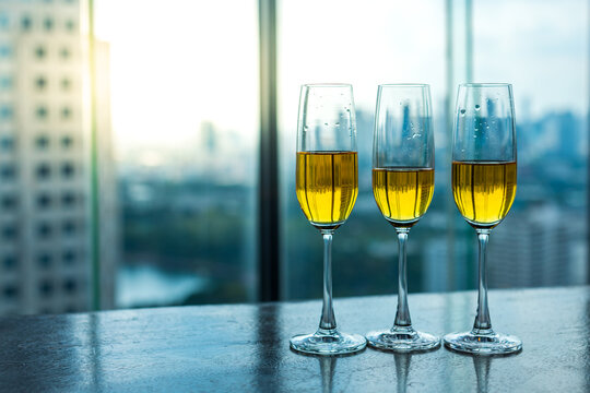 Picture of three champagne glasses lying on the wooden table with city scene behind