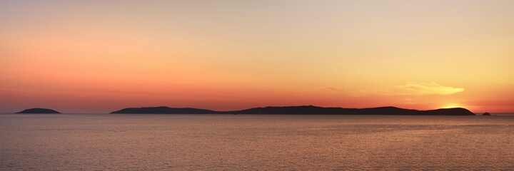 Isla de ons in the ria de pontevedra at sunset with the sun setting just behind