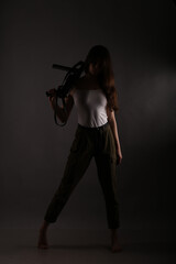 Long-haired brunette woman with vintage submachine gun in shadows