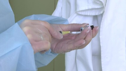 Vaccination against COVID-19, nurse in transparent protective gloves preparing vaccine for injection on vaccinal point for massive immunisation.