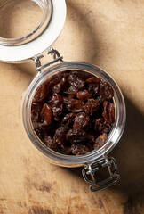 Raisins in a glass jar set against an old wooden background.
