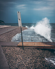 Breaking waves on promenade with warning sign in Slovenia