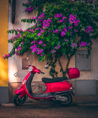 A red motorbike scooter parked in an alleyway of an ancient village in Italy. The scooter symbol of...