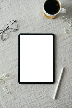 Blank screen tablet mockup, drawing pencil, glasses, coffee cup on linen tablecloth. Flat lay, top view. Elegant feminine workspace, nordic style