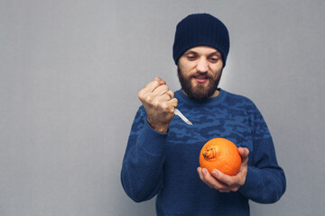 angry bearded man wants to cut out a large navel of an orange with a scalpel, the concept of...