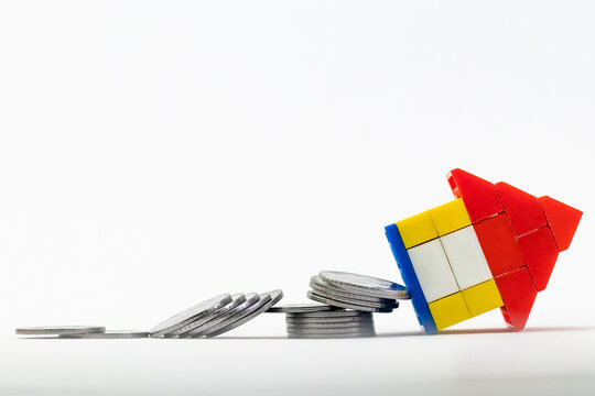 A toy house fell down from the column of coins in disaster and insurance concept.