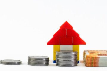 Defocused coins and money notes with a blocks house toy behind in Loan concept.
