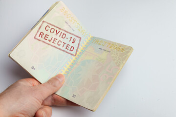 Fototapeta premium Concept representing a hand holding a vaccination passport with a stamp indicating that the passenger has been rejected because he doesn't have the vaccine requirements