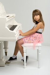 Young girl posing at white grand piano