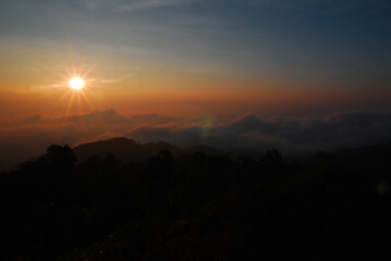 Landscape Tranquil scene of the sunrise with Orange sky and fog around the mountain in the morning at doi pha hom pok national park Thailand.