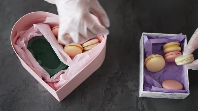Female hands puts macaroni in gift box at kitchen, top view