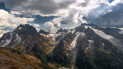 Epic landscape. A magnificent panorama of the Caucasus Mountains with sunlight in high resolution. Desktop wallpaper.