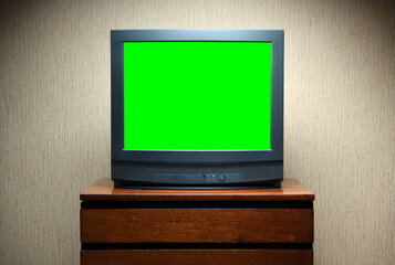 Antique TV with green screen on an antique wooden cabinet, old design in a house in the style of the 1980s and 1990s.
