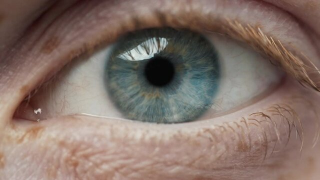 Eye Human Opening with Beautiful Blue Iris Macro Shot. Bright Beauty Female Open Eyes with Pupil Dilation. Extreme Close-up Girl Clear Looking at Camera. Contracting Eye Iris on Light. View Concept 4k