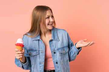 Teenager Ukrainian girl with a cornet ice cream isolated on pink background with surprise facial expression