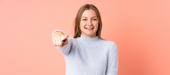 Teenager Ukrainian girl isolated on pink background surprised and pointing front